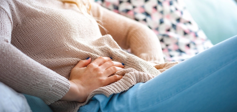 Femme allongée sur un canapé ayant mal au ventre